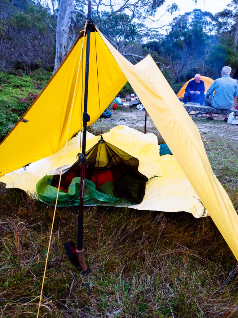 Tarp and sleeping shelter setup with hiking poles.
