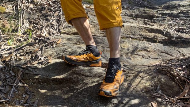 Legs of man wearing Ribelle Run shoes on a rock